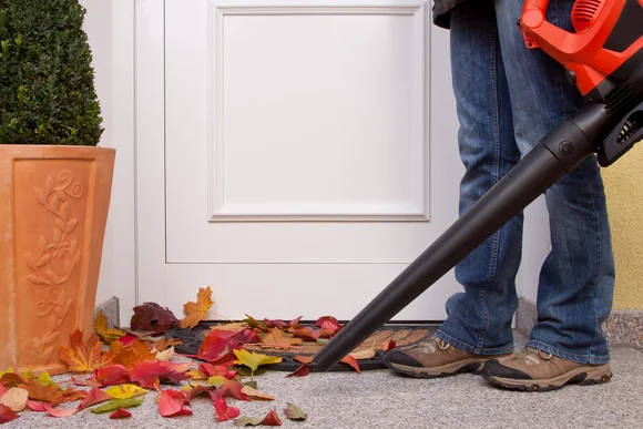 Person entfernt Laub mit einem Laubsauger.